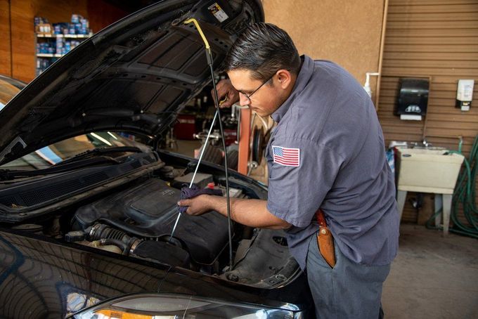 Mechanic inspecting a car engine with the hood open in an auto shop
