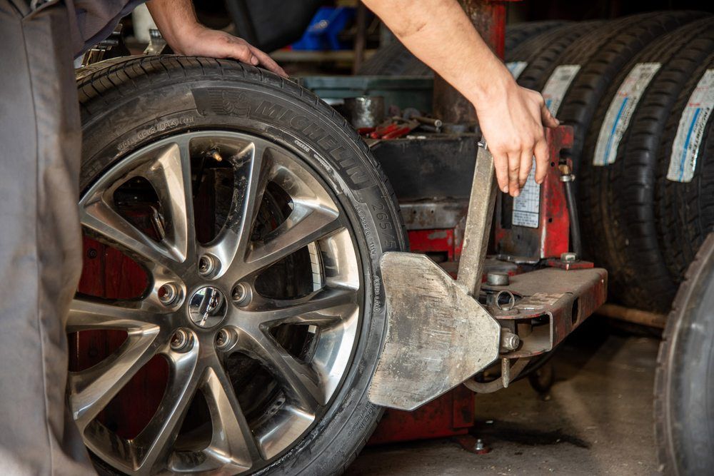 Mechanic mounting a car wheel on a tire-changing machine in an auto shop