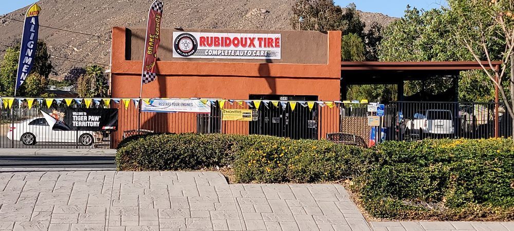 Rue Doux Tri sign on an orange brick entrance with black-and-yellow barriers and shrubs.