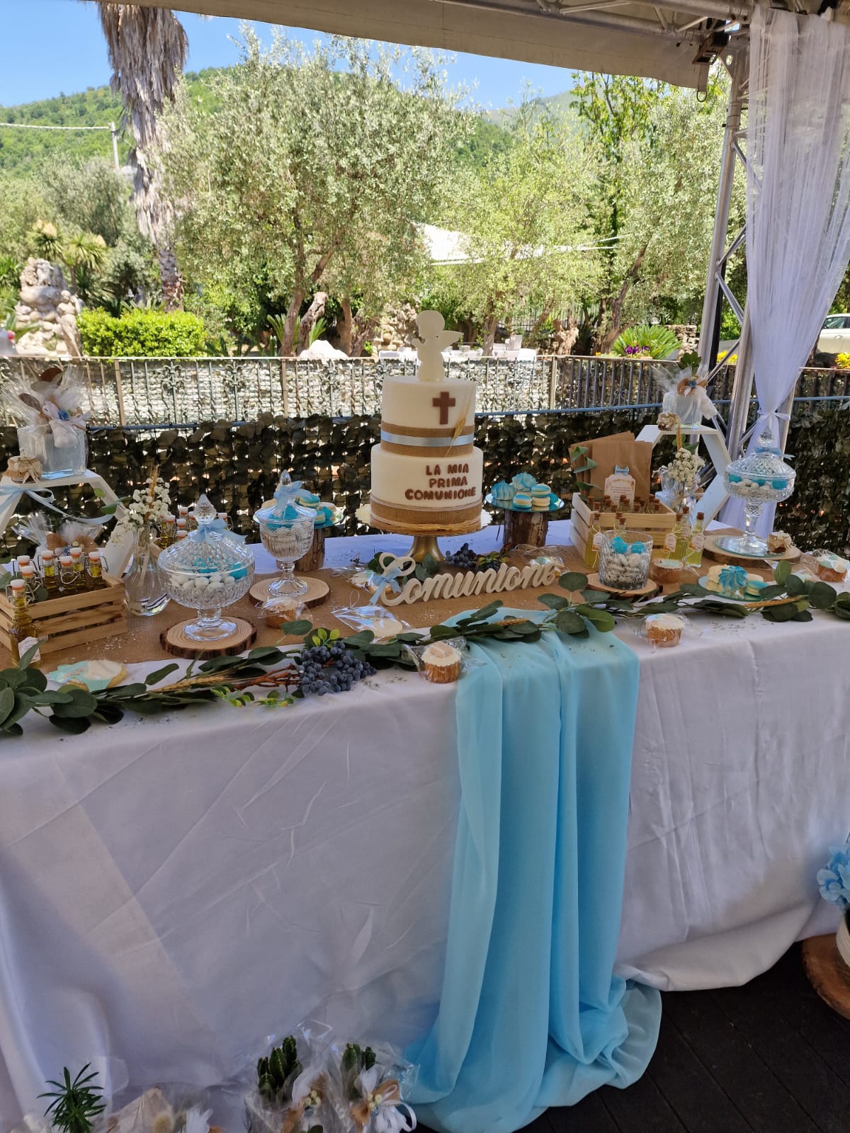 Un tavolo decorato per la prima comunione con sopra una torta e dei dolcetti.