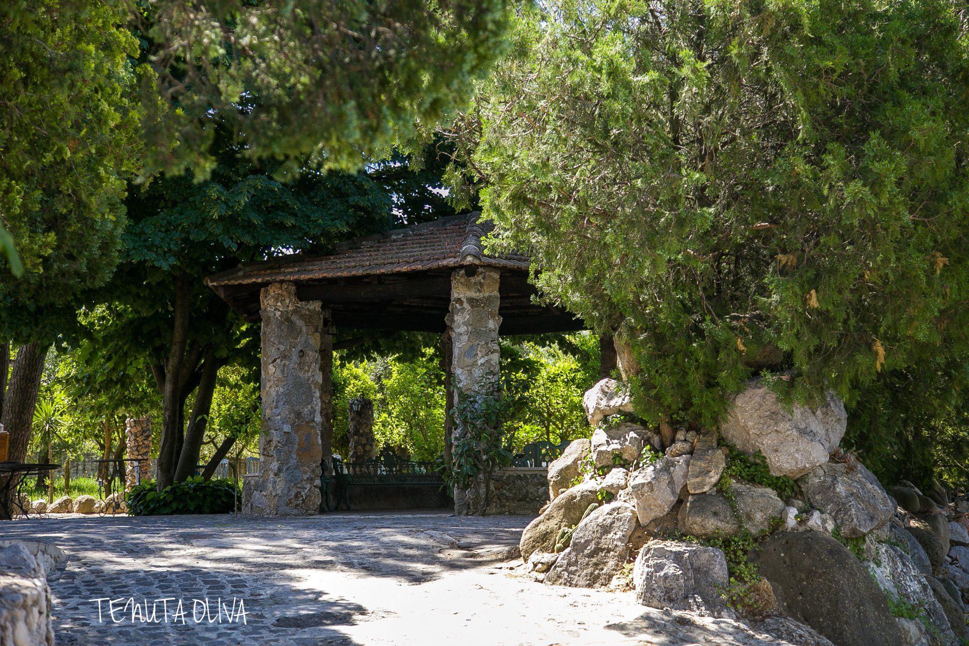Un padiglione in pietra circondato da alberi e rocce in un parco.