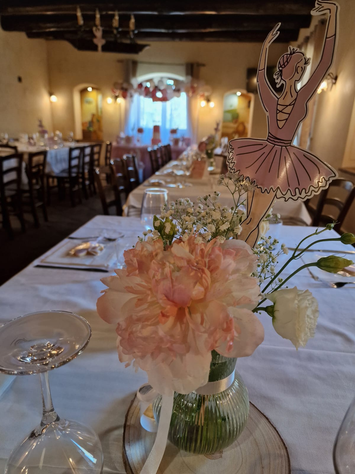 Un tavolo con un vaso di fiori e una ballerina sopra