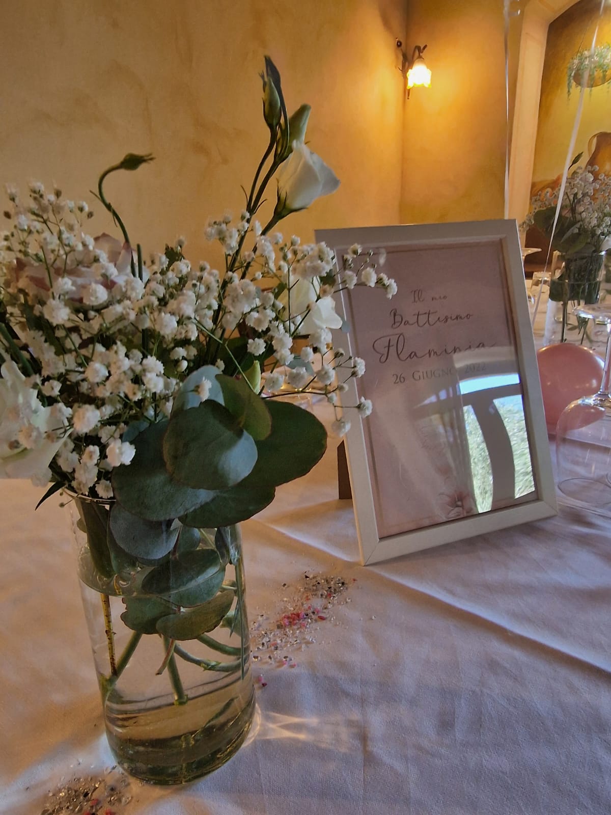 vaso pieno di fiori e un cartello su un tavolo.