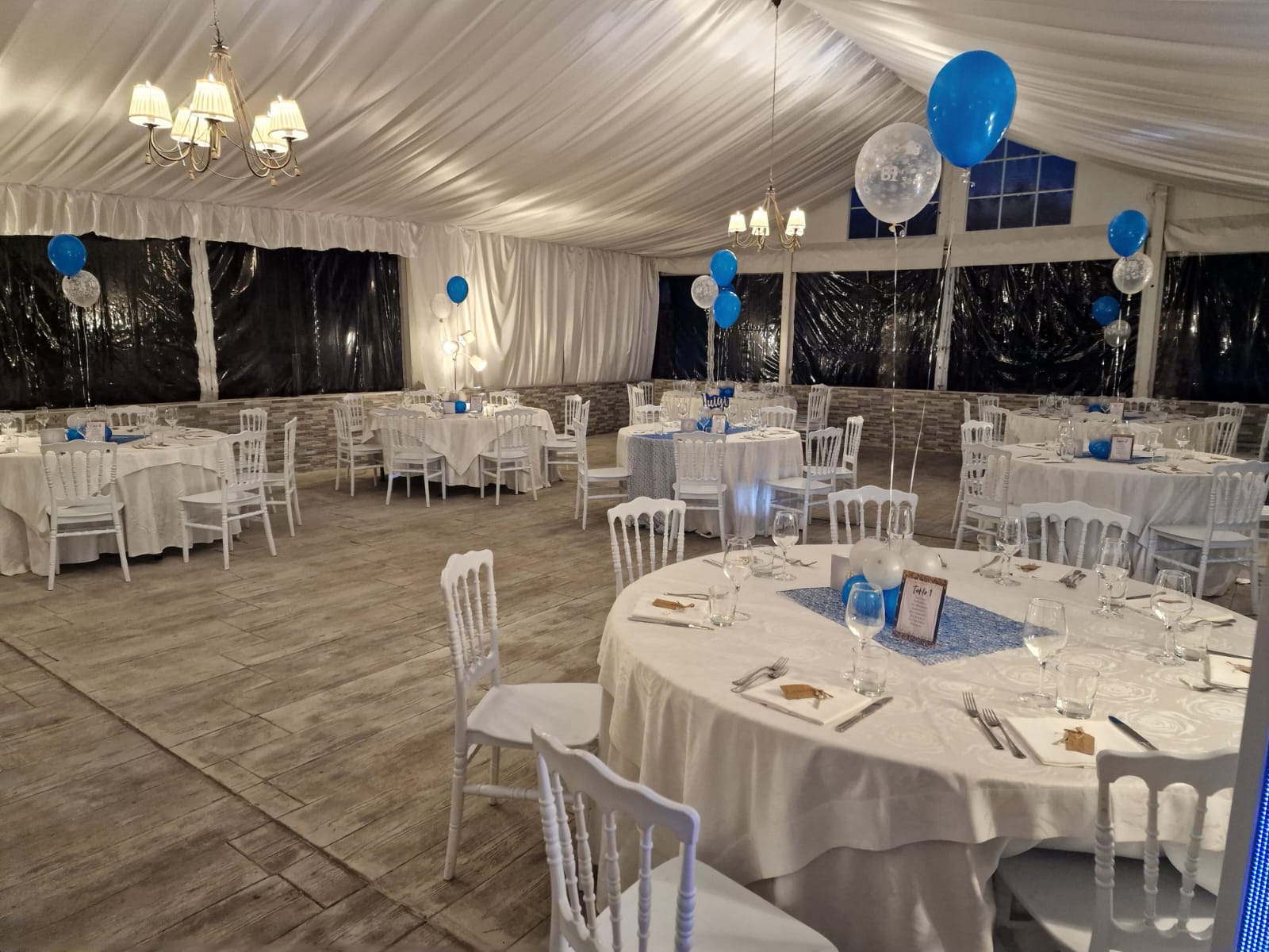 una grande sala con tavoli e sedie allestita per un ricevimento di nozze
