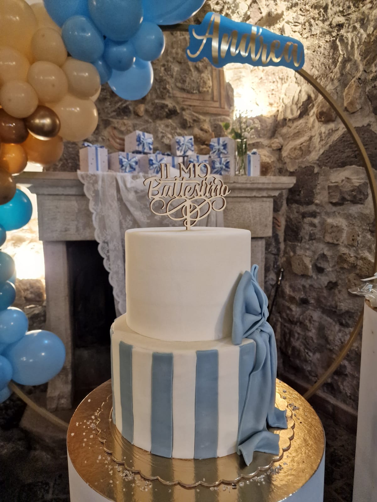 Una torta è appoggiata su un tavolo con dei palloncini sullo sfondo.