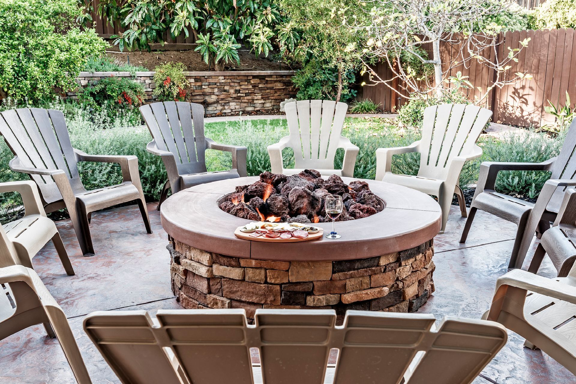 A fire pit is surrounded by chairs on a patio.