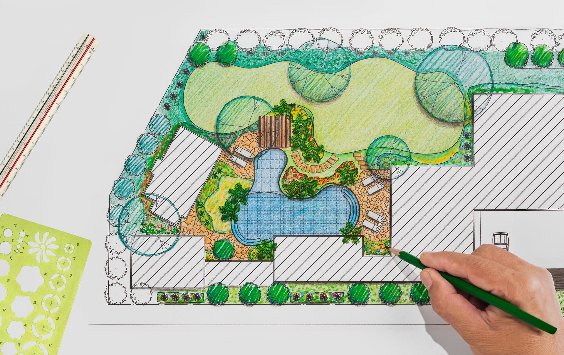 Hand drawing a colorful landscape plan with trees, paths, and blue water features on paper