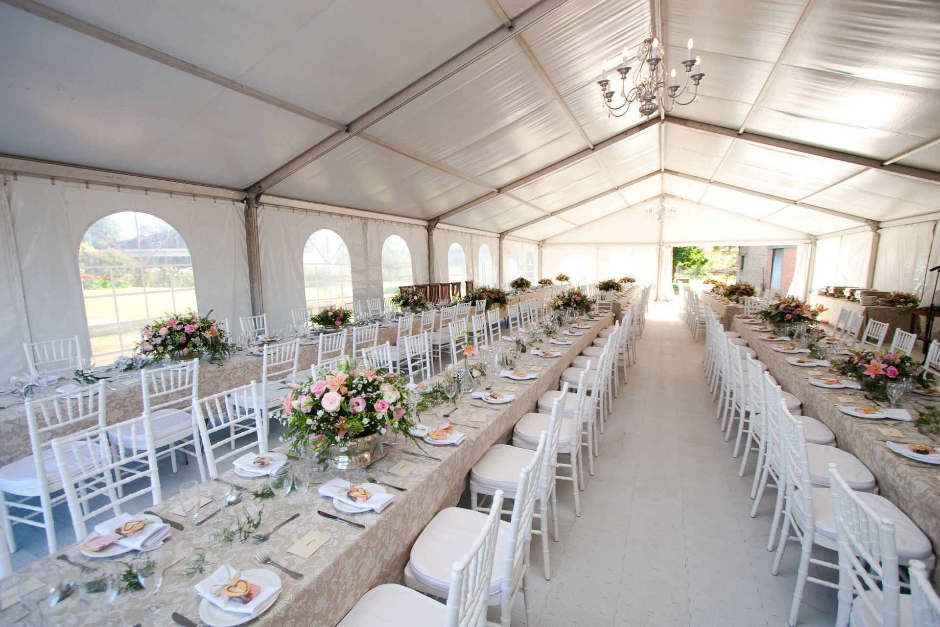 The inside of a massive white wedding tent with tables and chairs already in position.
