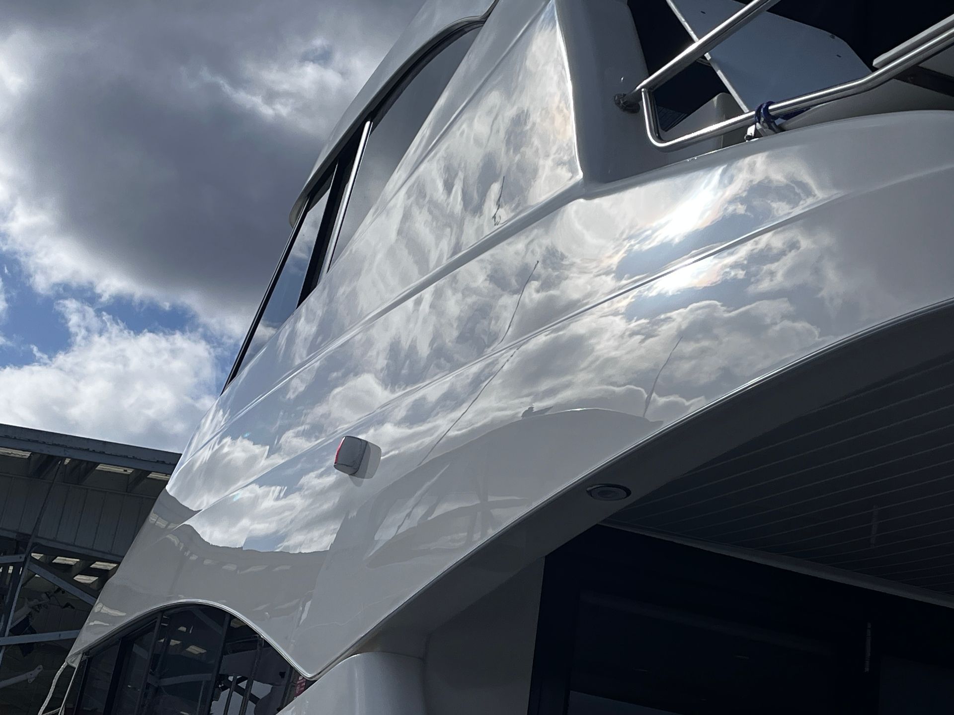 A close up of the side of a boat with a cloudy sky in the background.