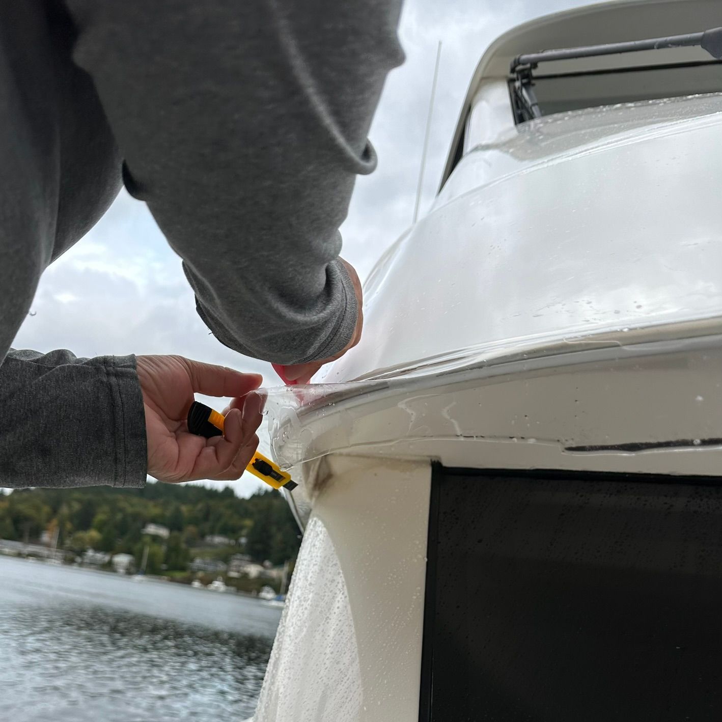 A person is working on the side of a boat with a screwdriver.