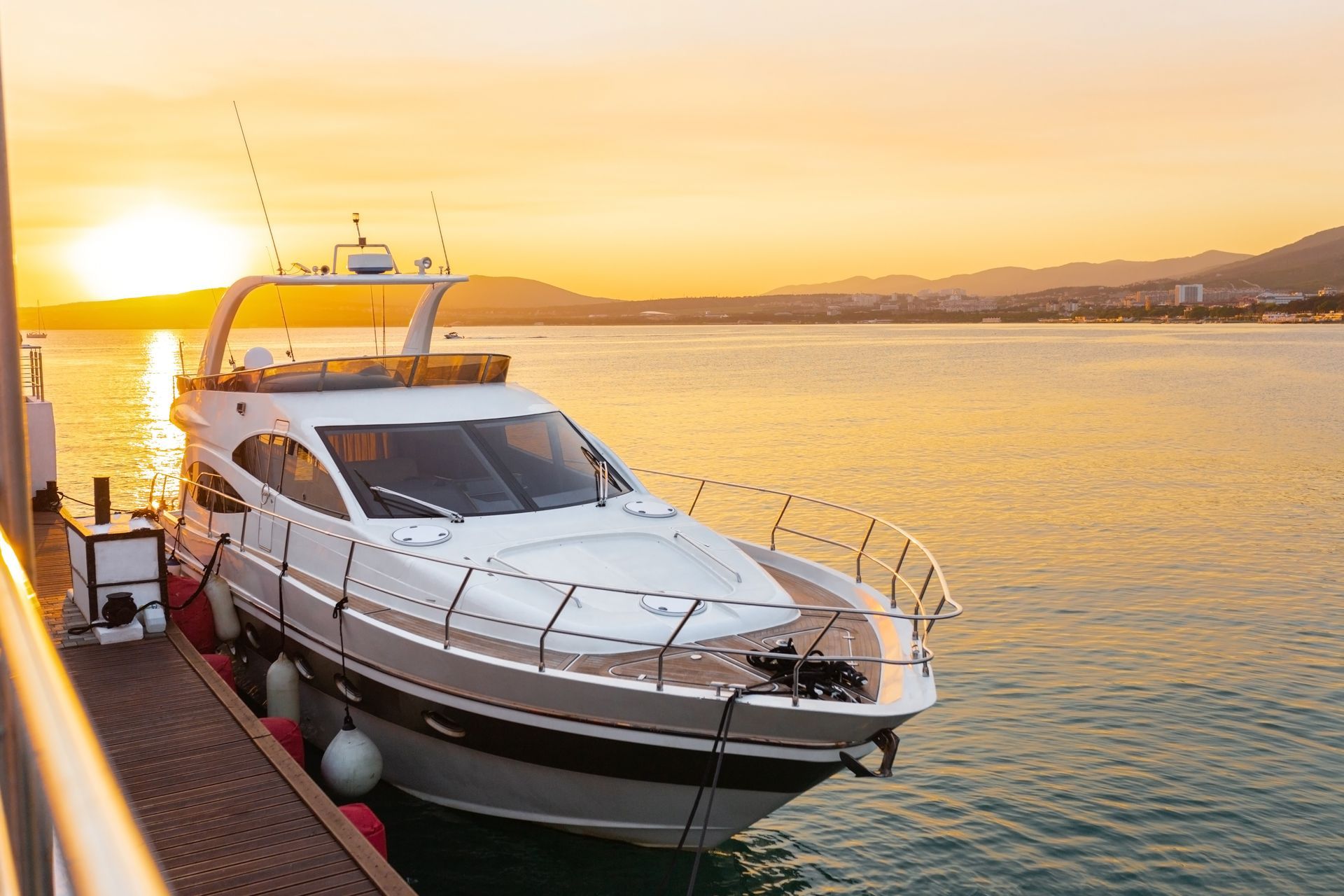 A yacht is docked at a dock in the water at sunset.