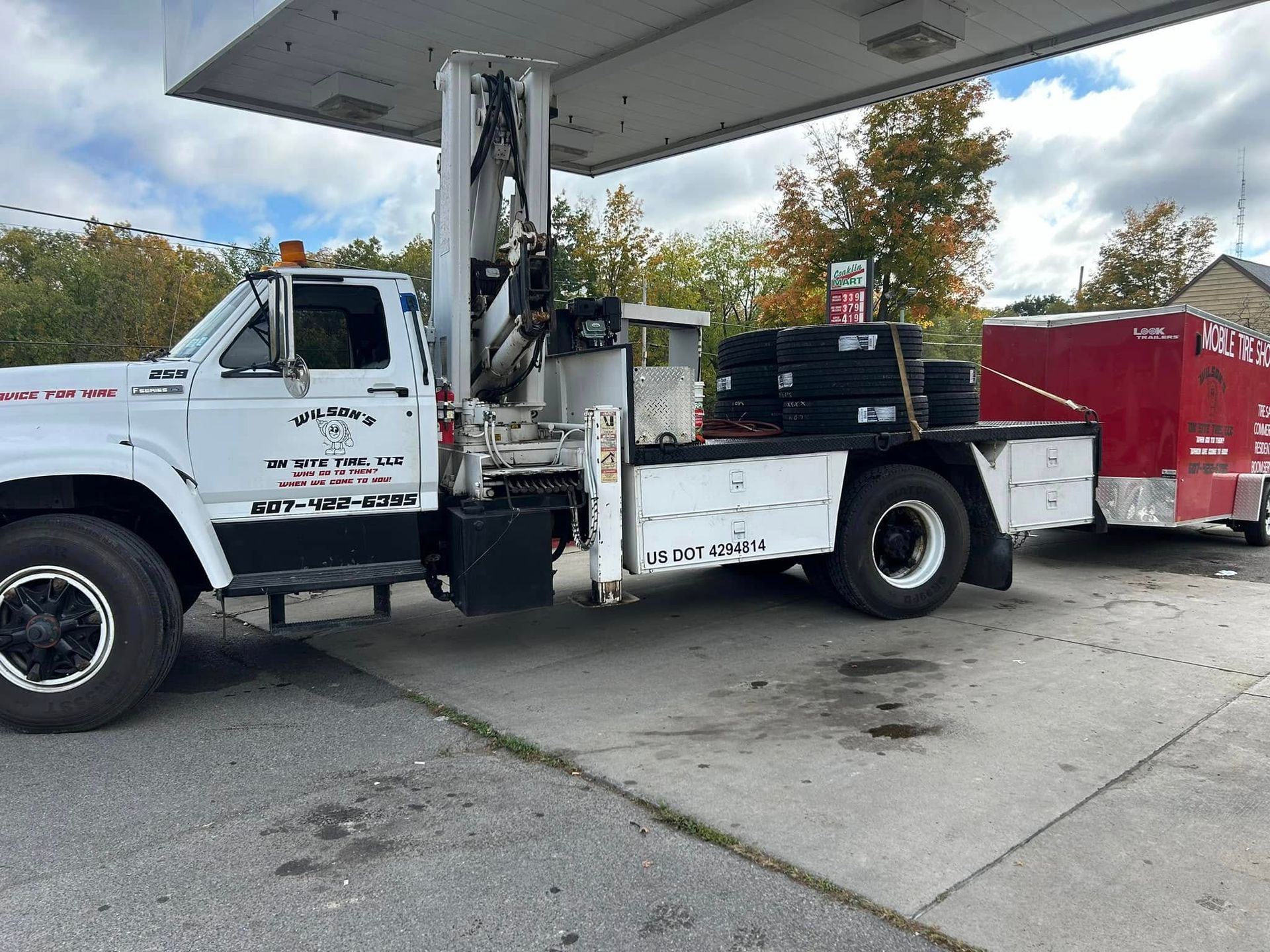 A tow truck is parked under a gas pump at a gas station.