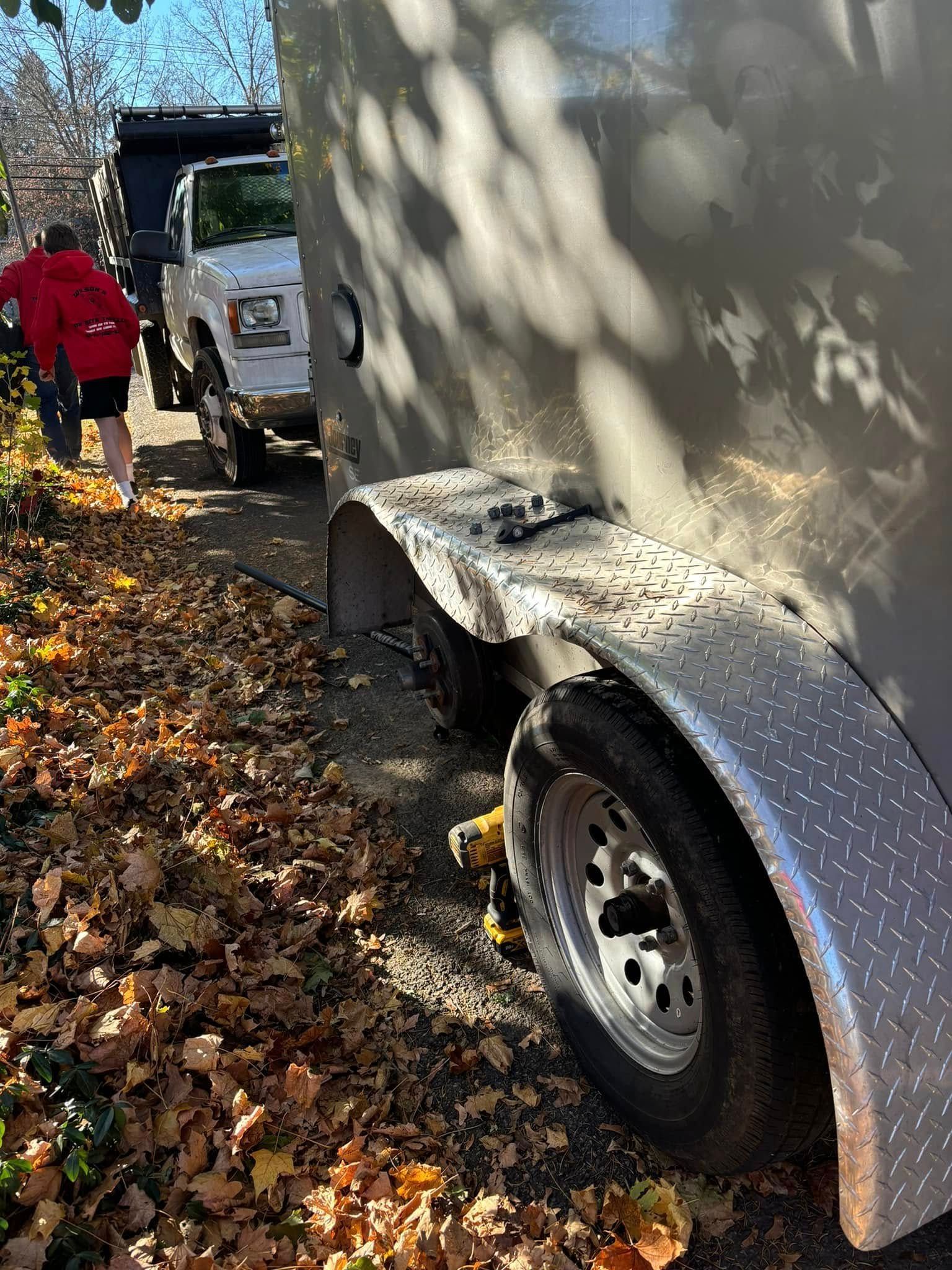 A trailer is parked on the side of the road next to a truck.