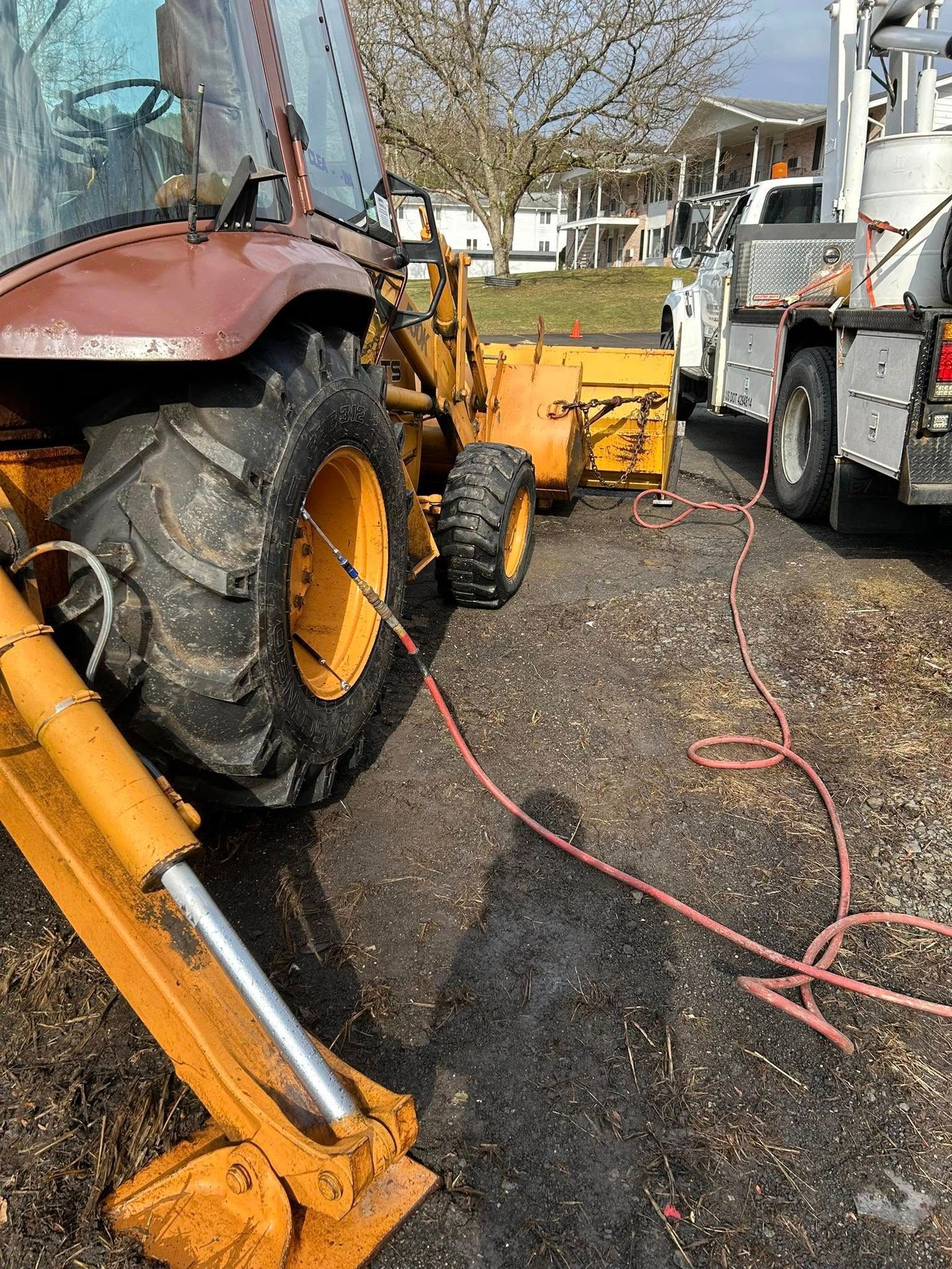 A tractor is being towed by a truck in a parking lot.