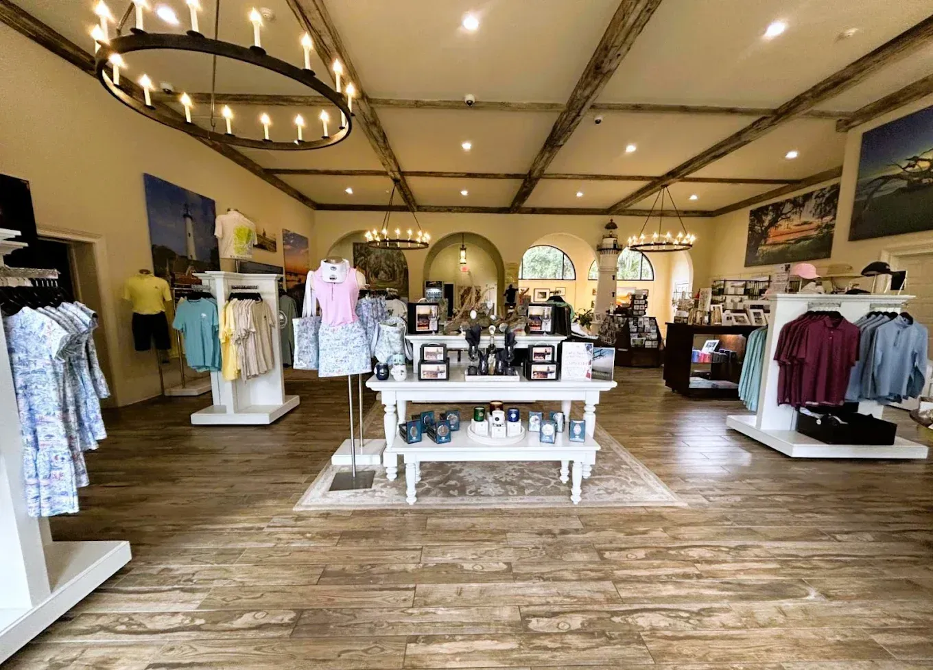 Interior of a gift shop with clothing racks, a display table, and decorative lighting.