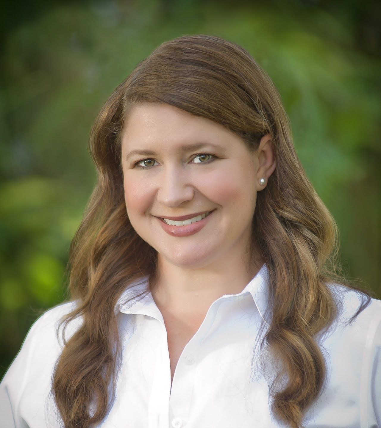 A woman in a white shirt is smiling for the camera.