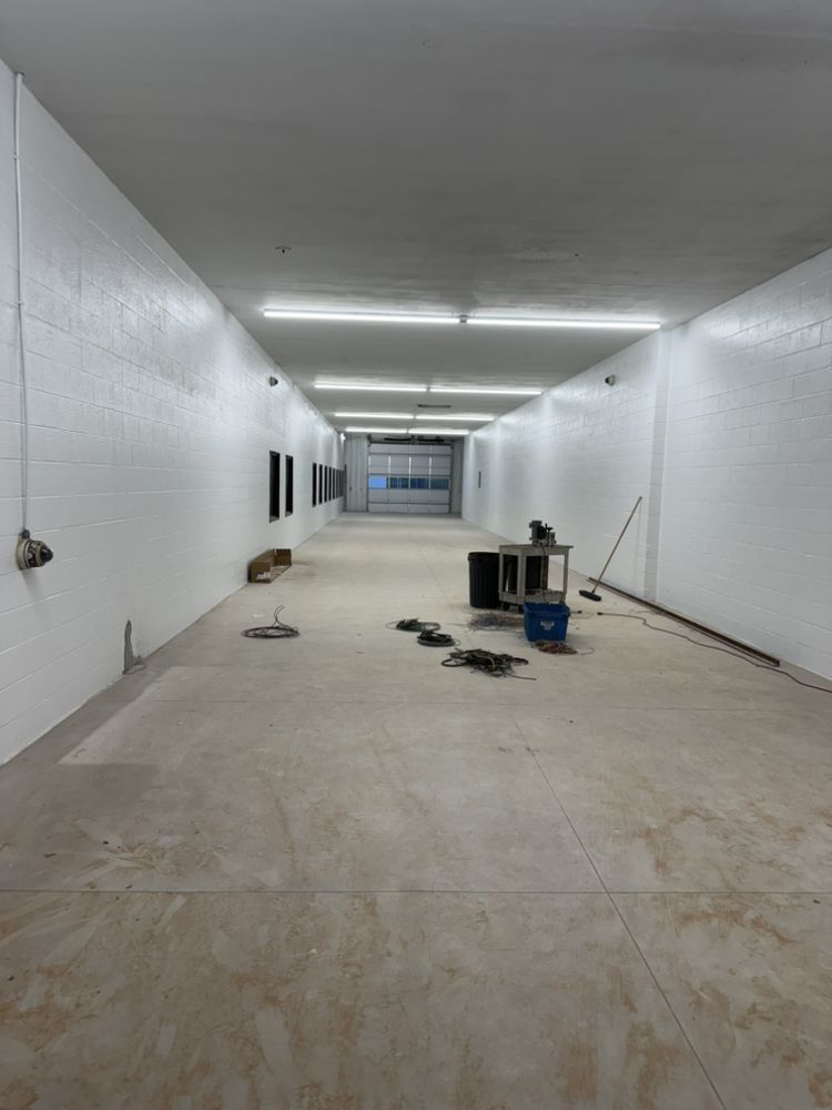 Empty white hallway under construction with tools and debris on the floor