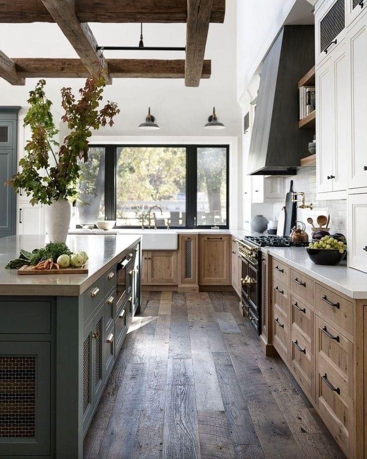 Rustic modern kitchen with wood island, white cabinets, and large window overlooking trees