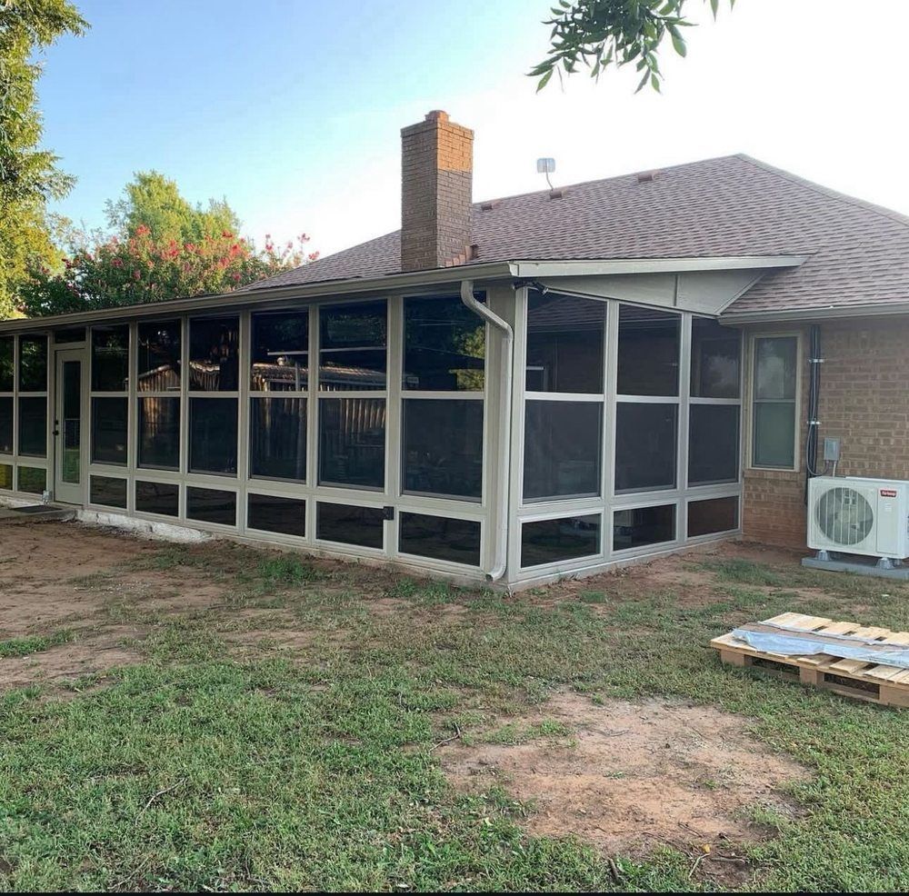 Screened backyard patio with brick chimney, white framing, and screened windows beside a lawn