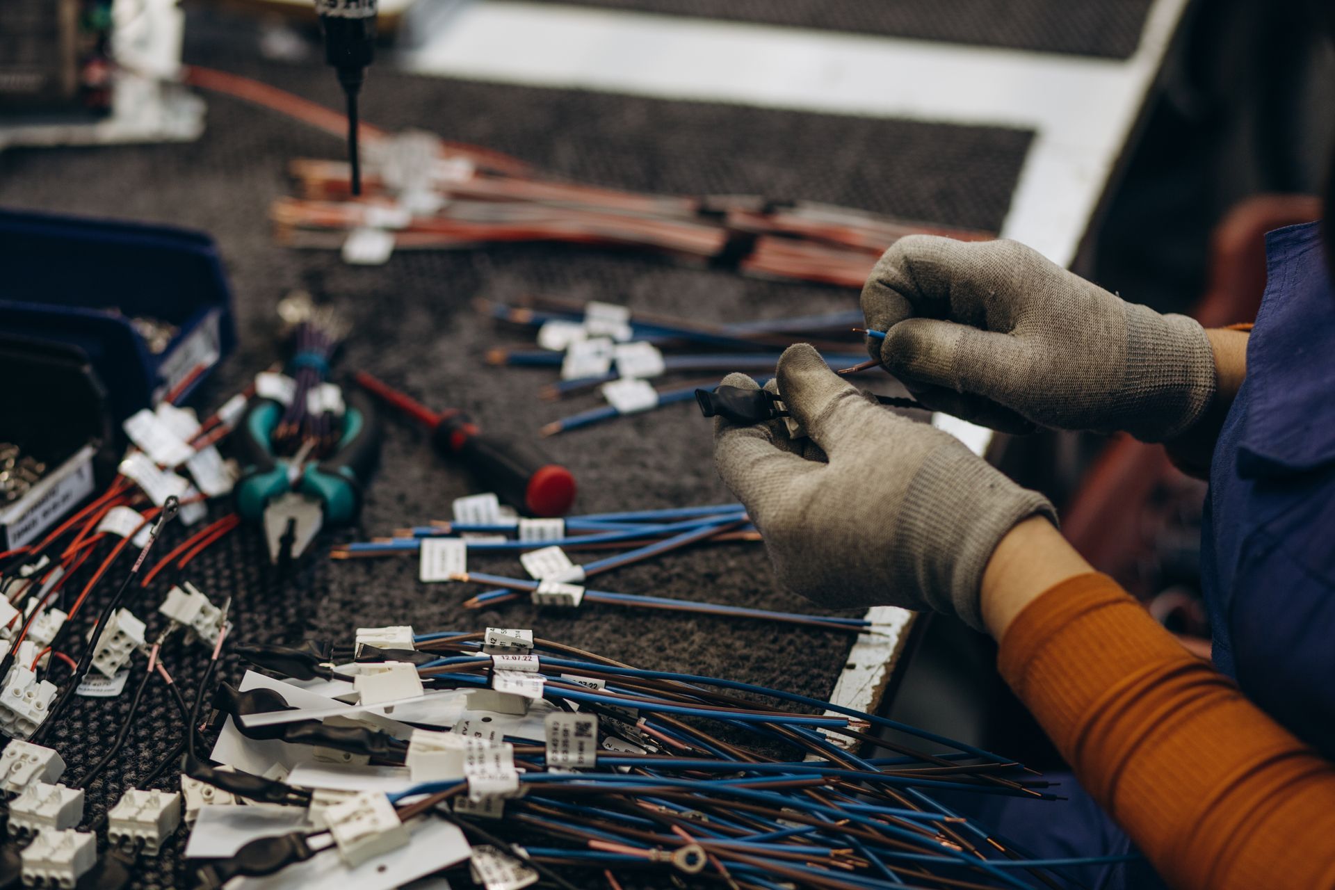 A woman is working on electrical wires in a factory.