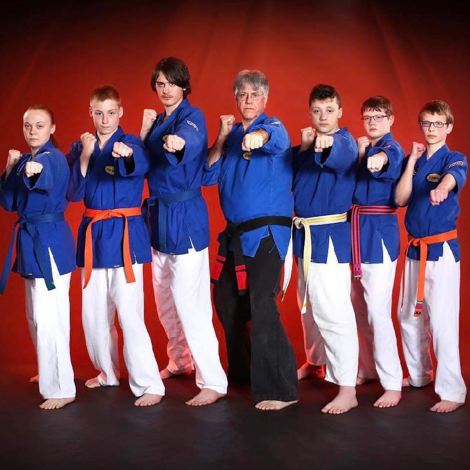 A group of karate fighters are posing for a picture