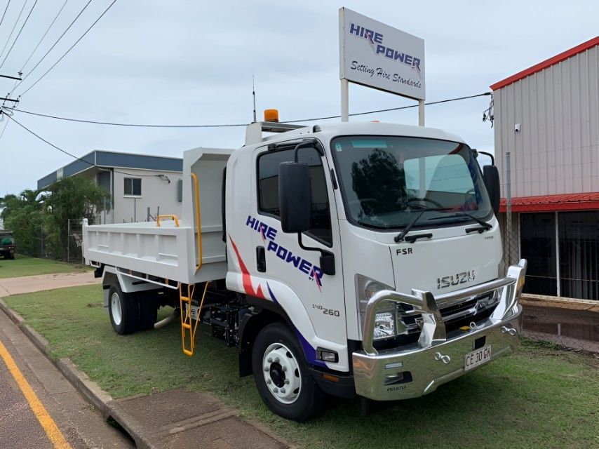 A White Dump Truck is Parked on the Side of the Road in Front of a Building — Hire Power NT in Berrimah, NT