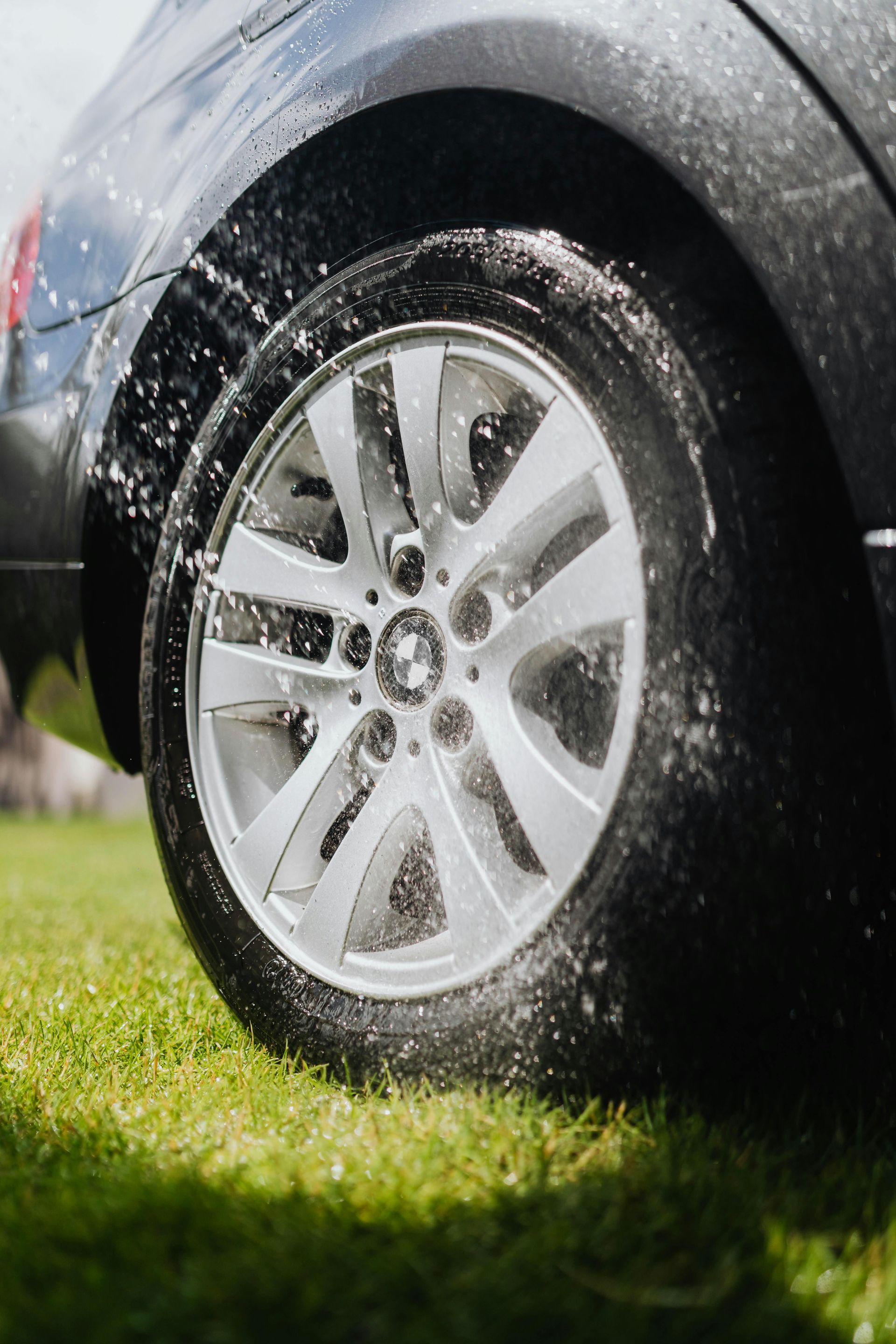 A close up of a car wheel with water splashing on it.