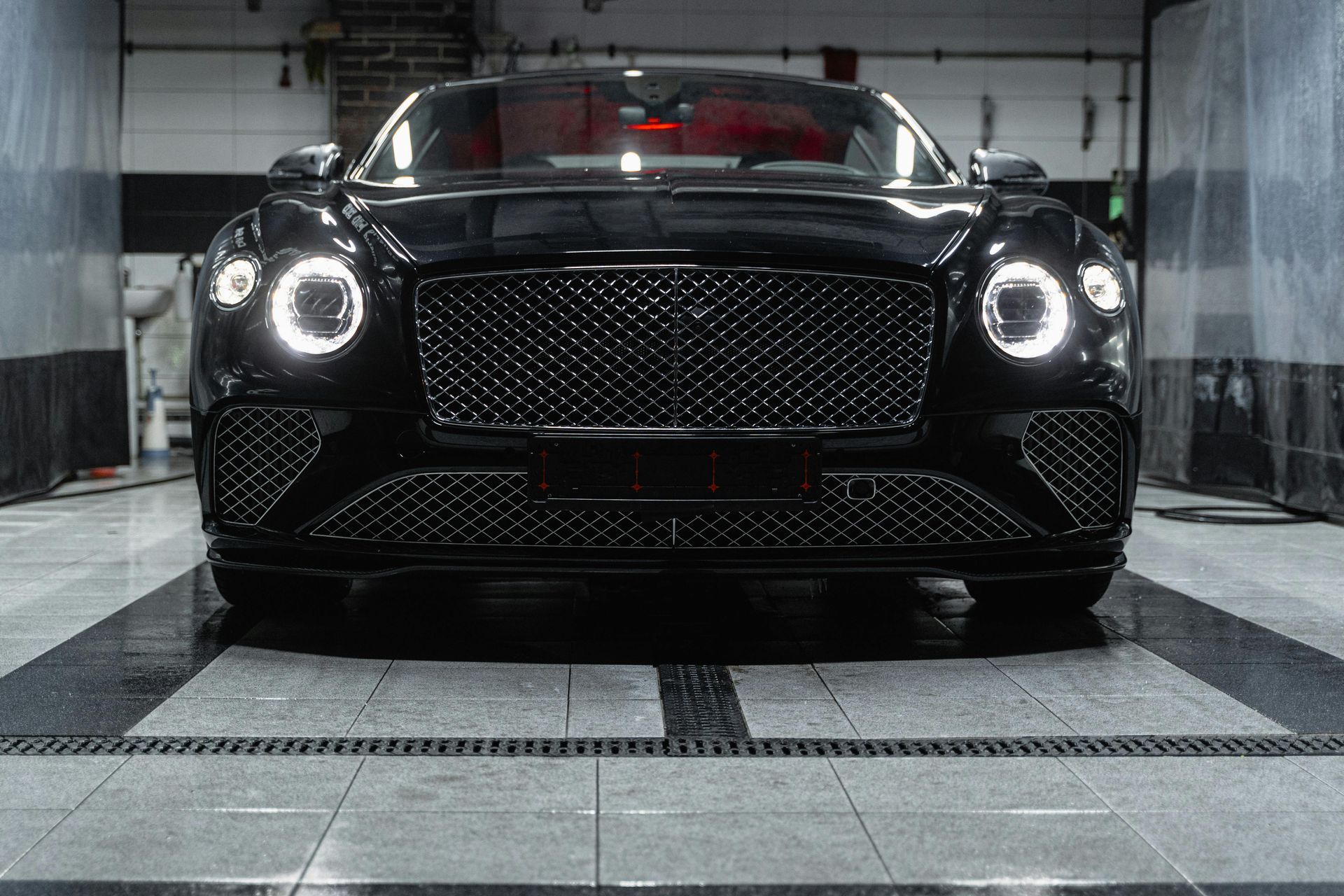 A black bentley is parked in a car wash
