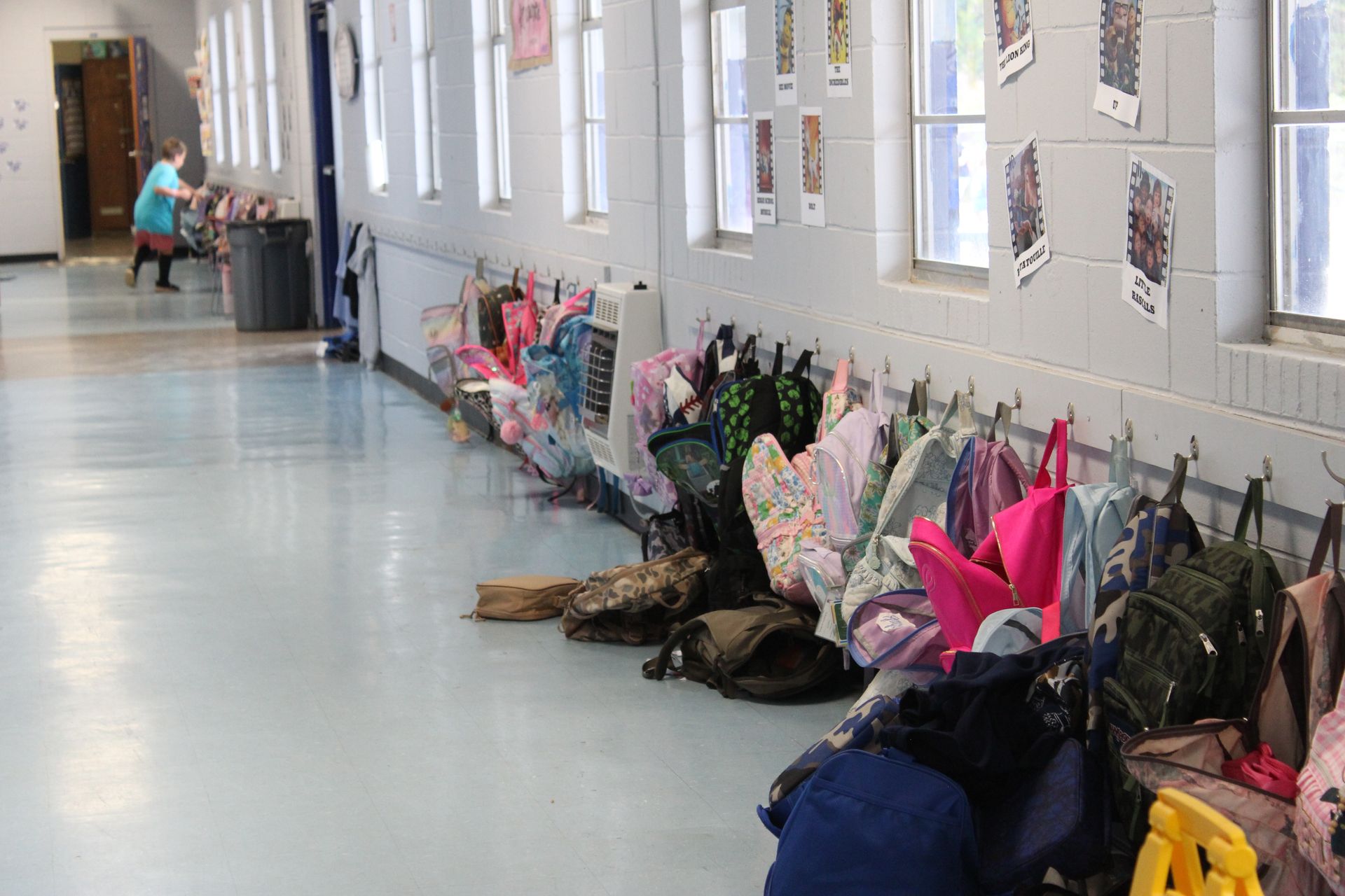 School hallway lined with colorful backpacks and coats against the wall