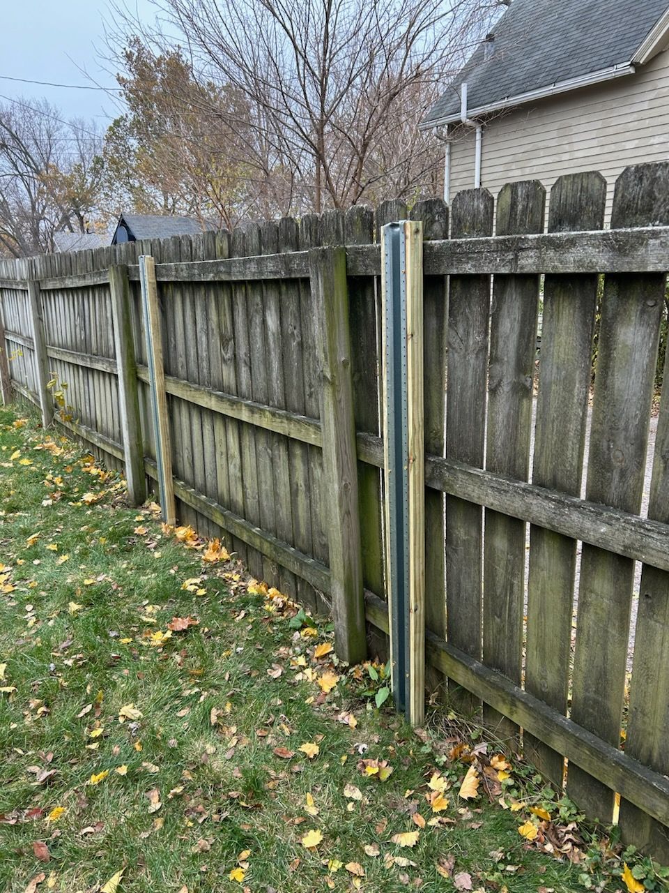 A wooden fence is sitting in the grass next to a house.
