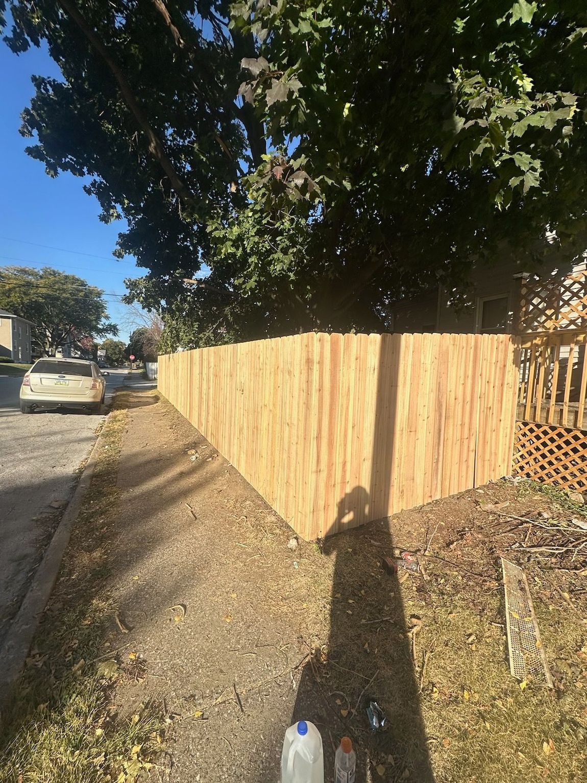 A wooden fence on the side of the road next to a tree.