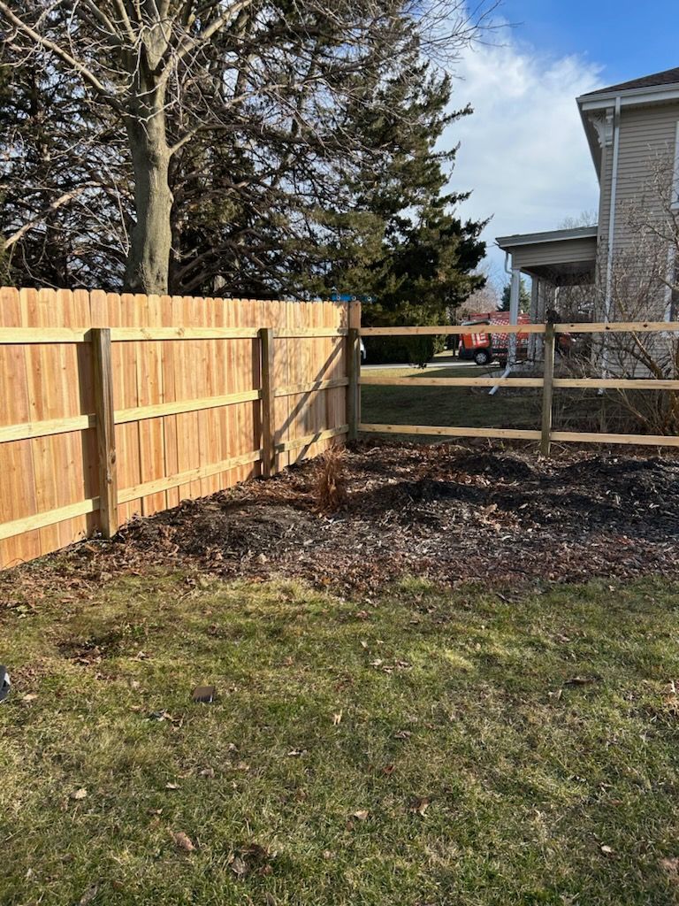 A wooden fence is in the backyard of a house.