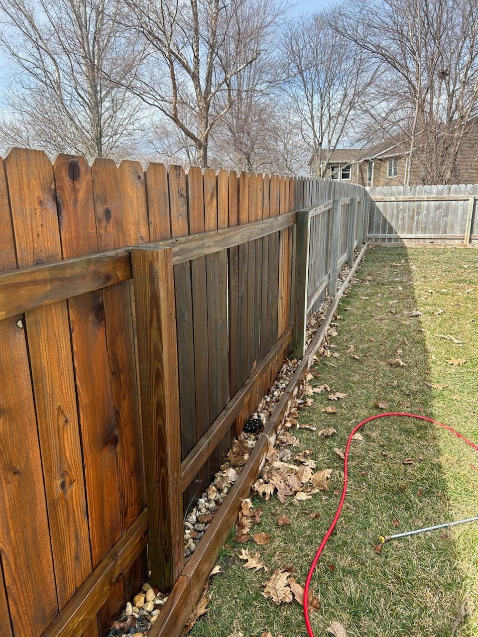 A wooden fence is sitting in the middle of a lush green yard.