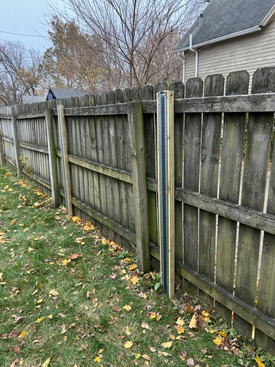 A wooden fence is sitting in the grass next to a house.