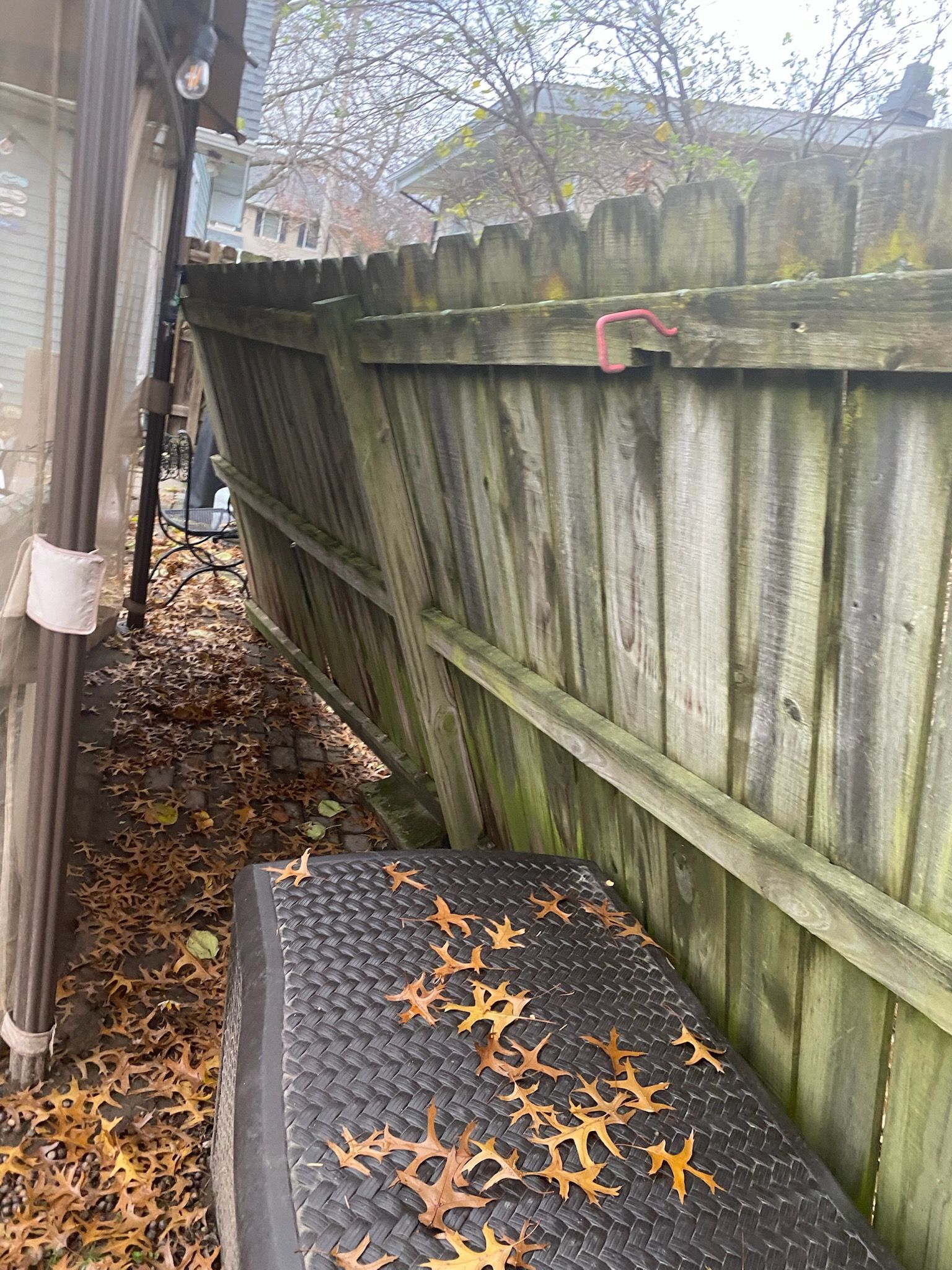 A wooden fence is surrounded by leaves and a black box.