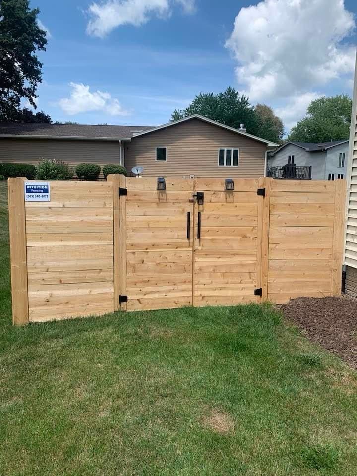 A wooden fence with a gate in front of a house.