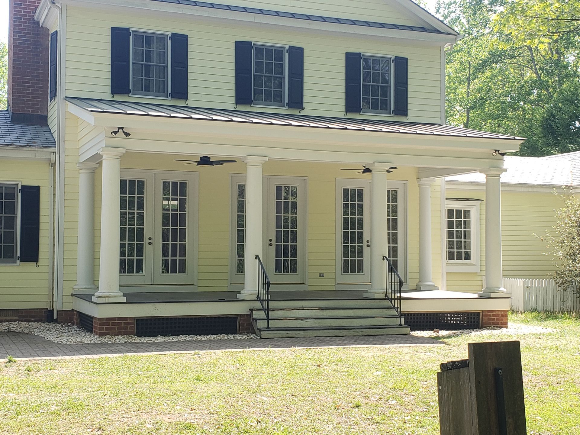 White two-story house with black shutters and a front porch, viewed from the yard.