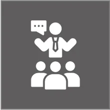 A white icon on a dark gray background showing a person addressing a group of three people, with a speech bubble above them.