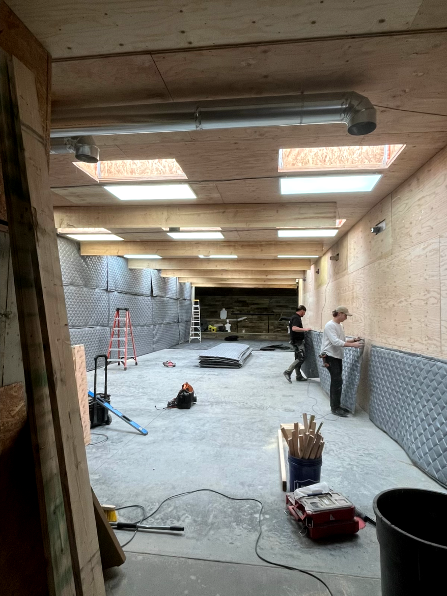Interior view of a building under construction. Workers are installing wall paneling.