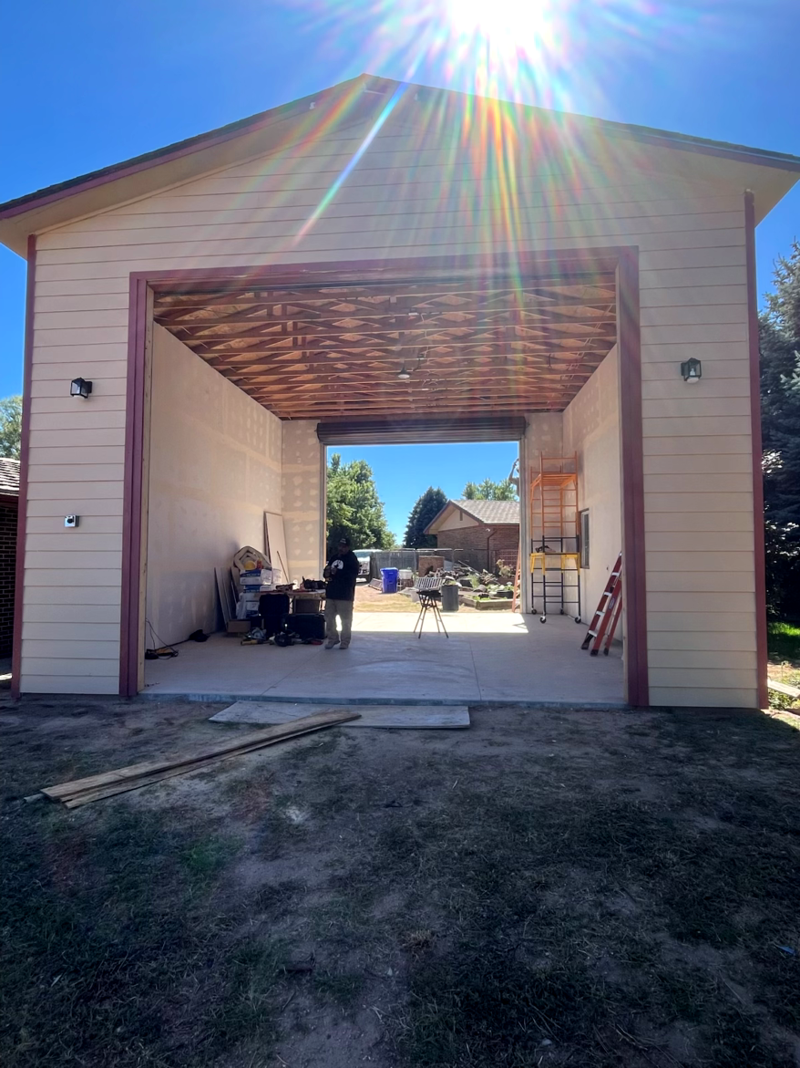 Open garage with a sunny exterior, revealing a glimpse of the backyard.