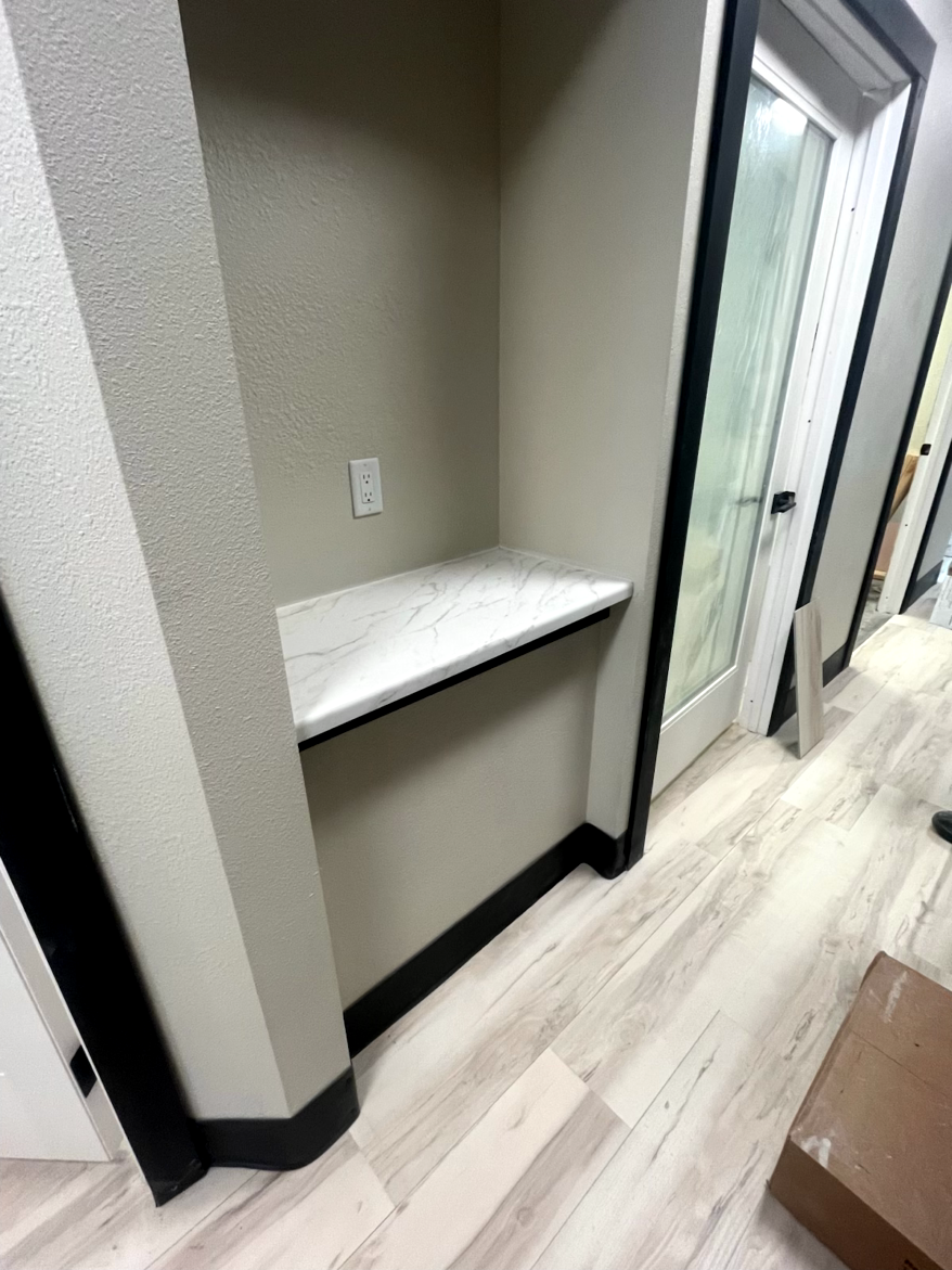 Built-in desk nook with a white countertop, beige walls, and a power outlet. Black trim.