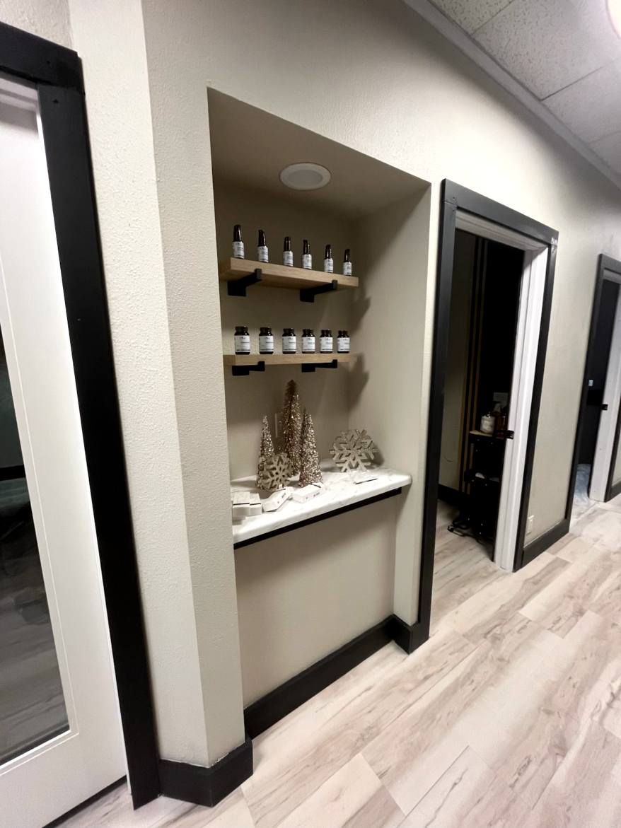 Hallway with a recessed alcove displaying products on shelves, decorated with small trees. Black trim.