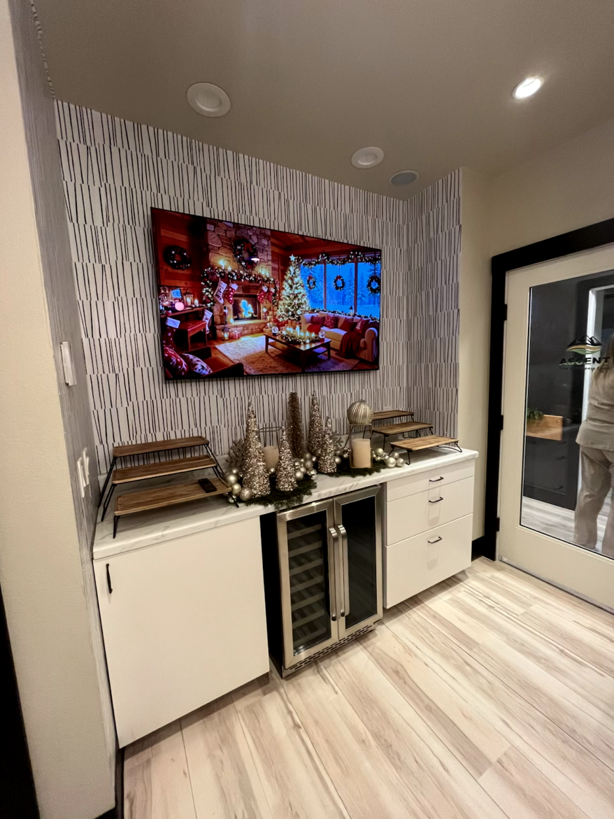 A room with a TV, a built-in bar with a wine cooler, and Christmas decorations.