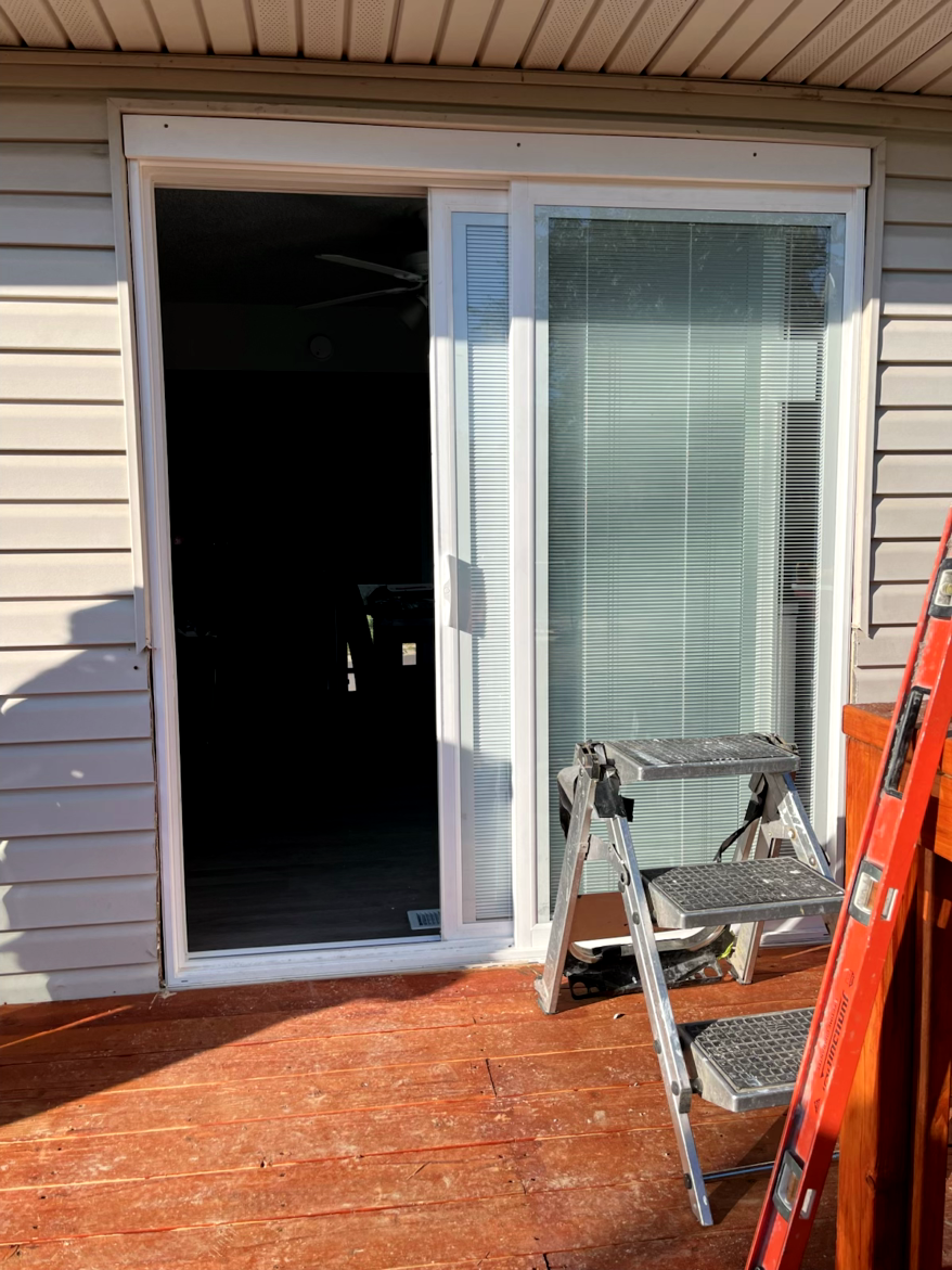 Sliding glass door open to a dark interior; small stepladder and red deck.