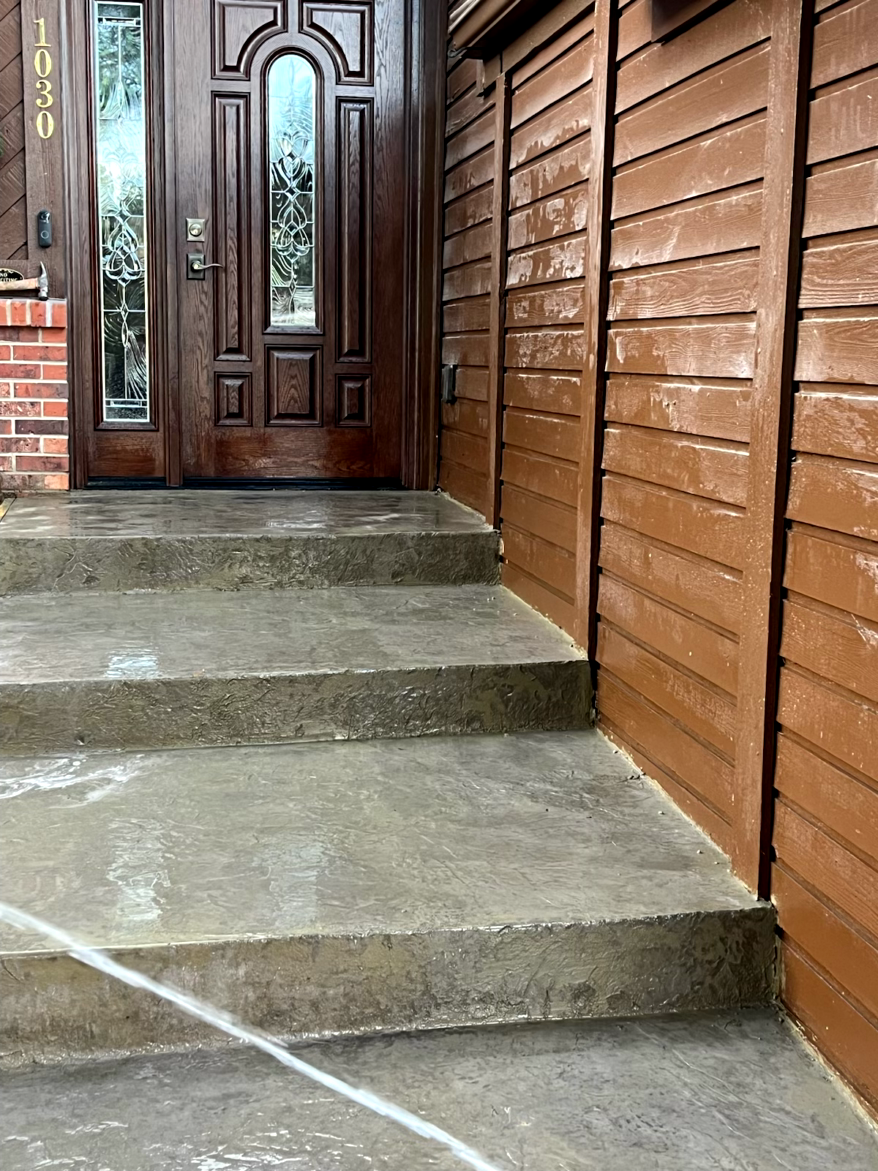 Brown door and steps being pressure washed; brown siding to the right.