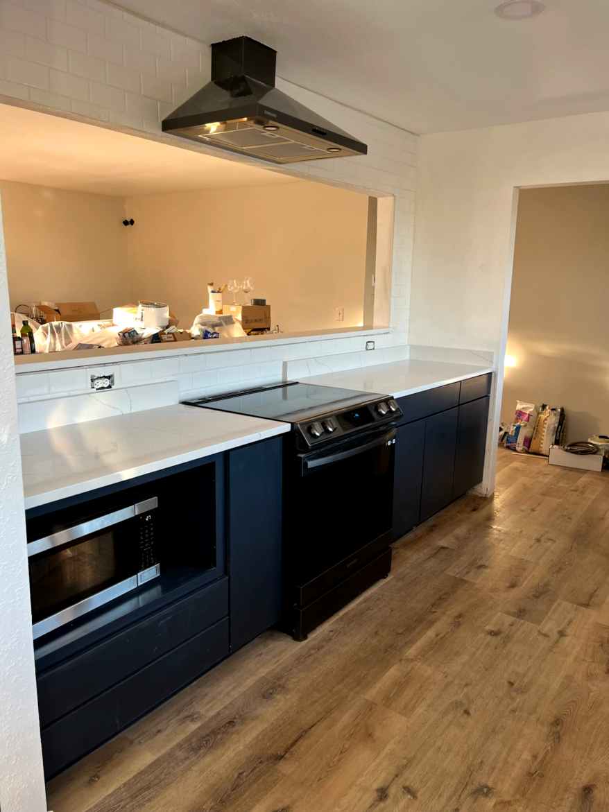 Navy blue kitchen cabinets with white countertops, a black stove, and a microwave.