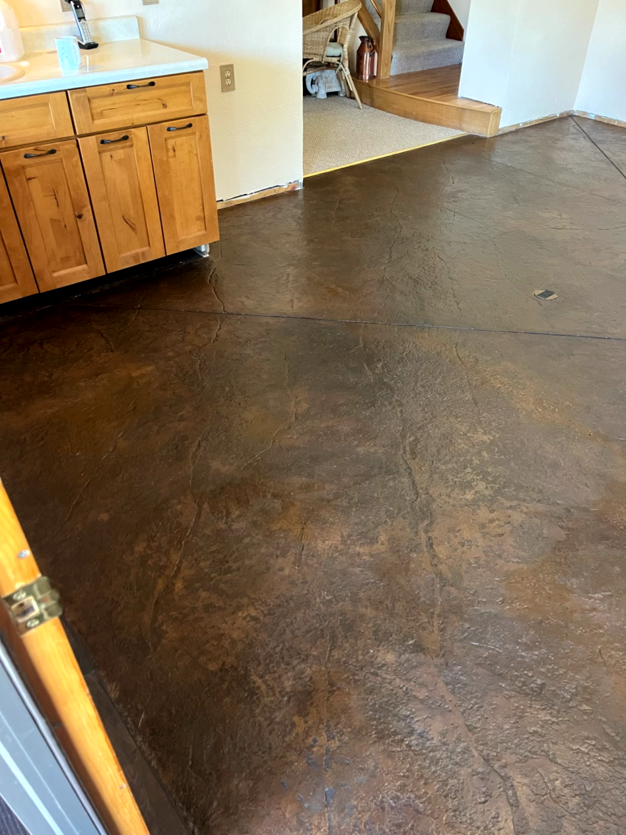 Brown stained concrete floor. Kitchen cabinets visible to the left.