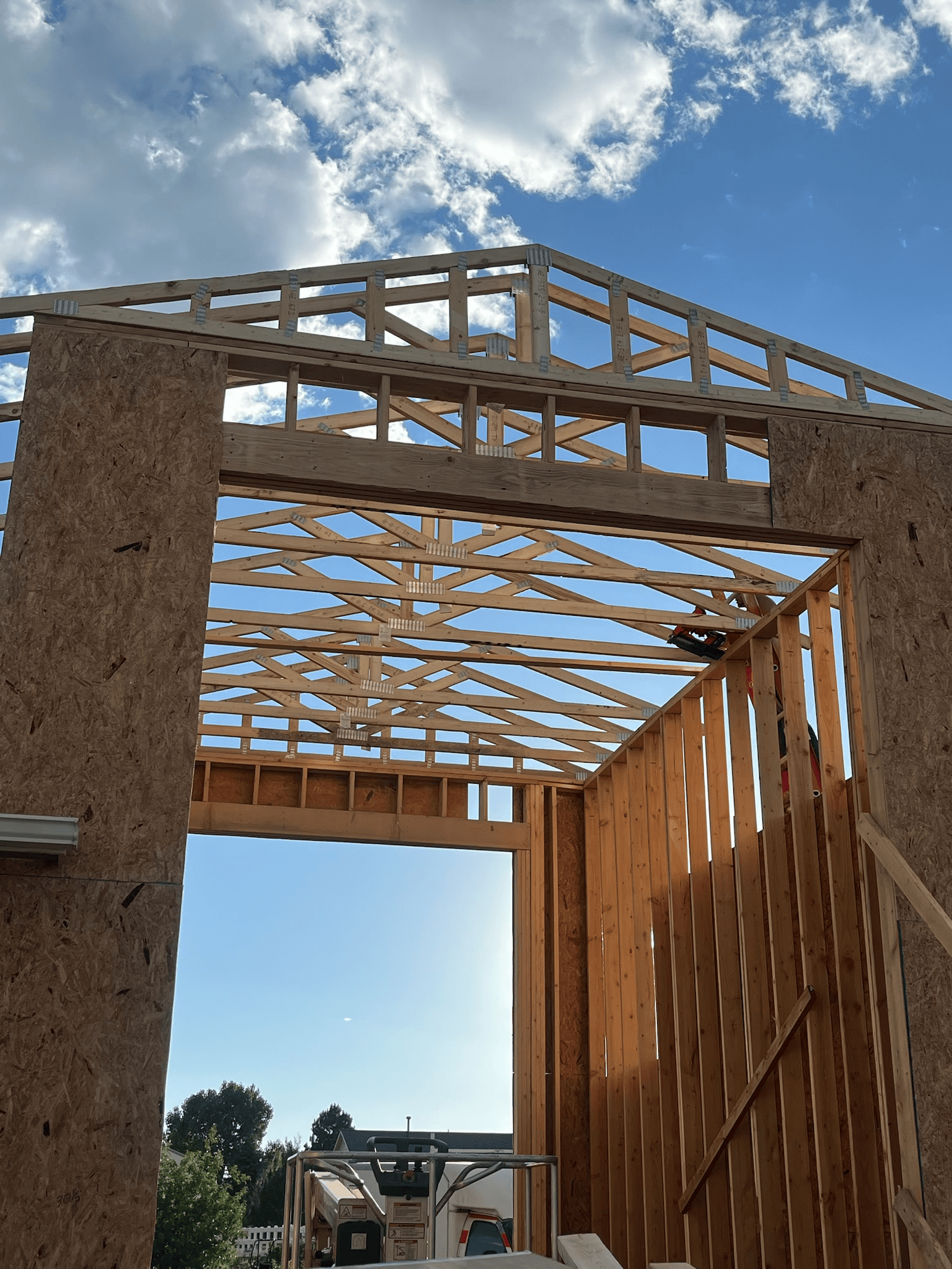 Wood frame construction of a building against a cloudy blue sky.