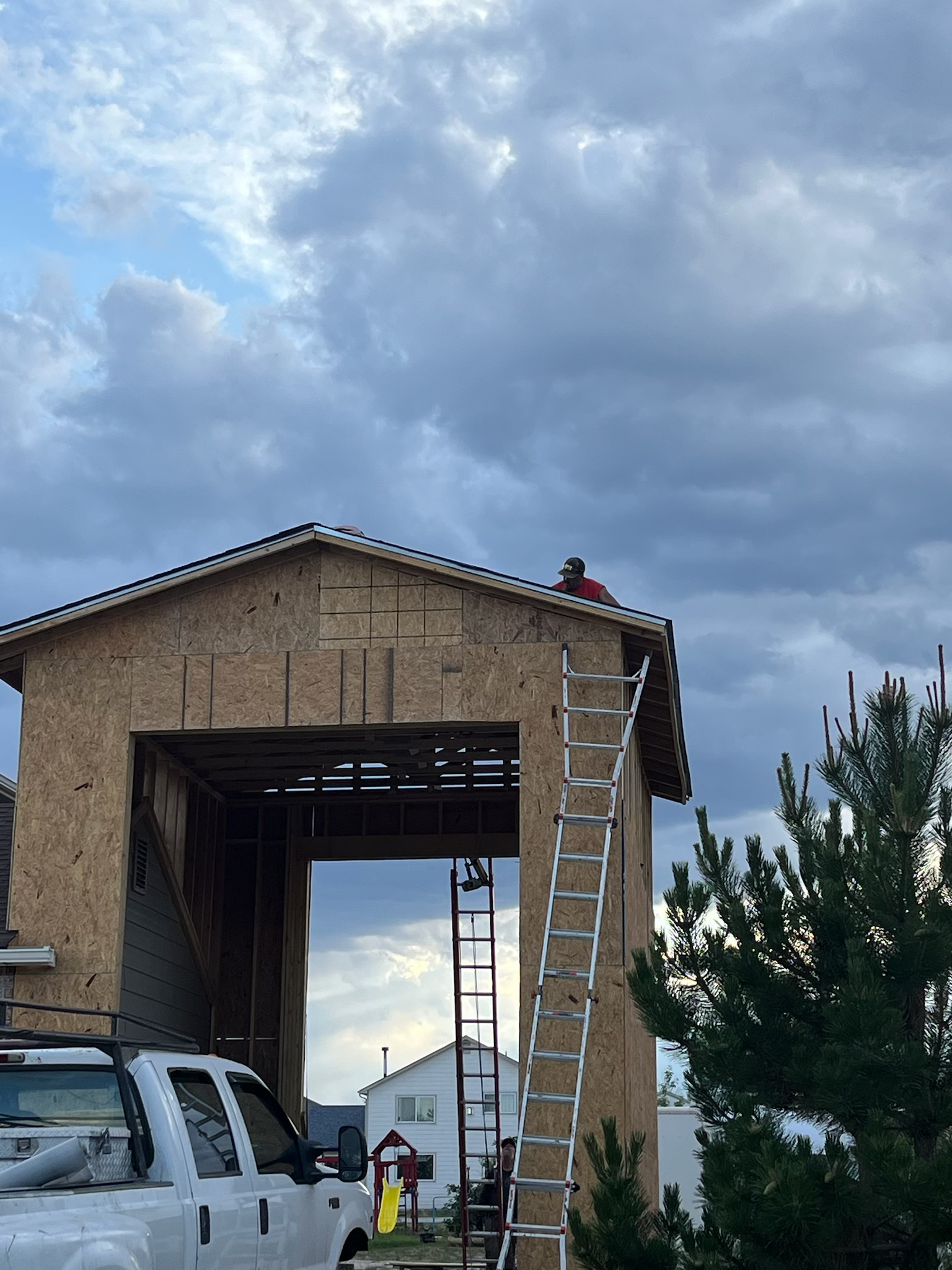 Construction site with workers, wooden structure, ladders, and overcast sky.