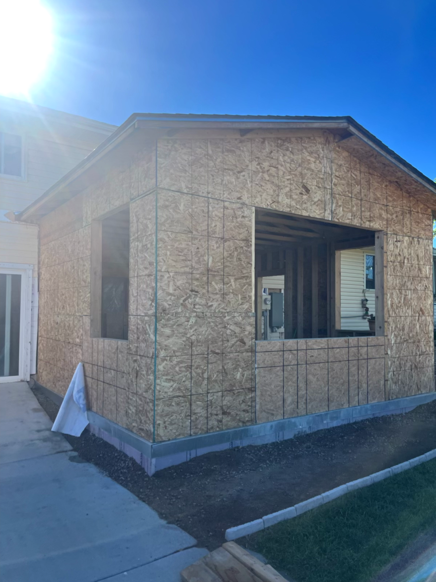 Exterior of a new construction home addition. OSB siding, window frames, and unfinished concrete base.